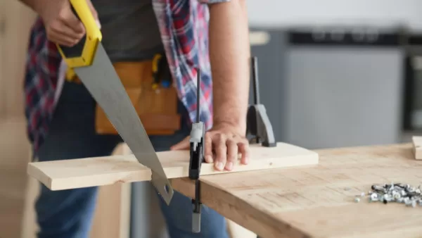 carpenter sawing wood with a handsaw